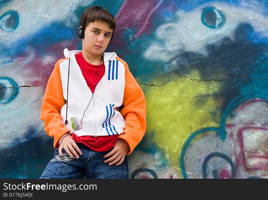 Portrait of a cool teenager listening music against a graffiti background