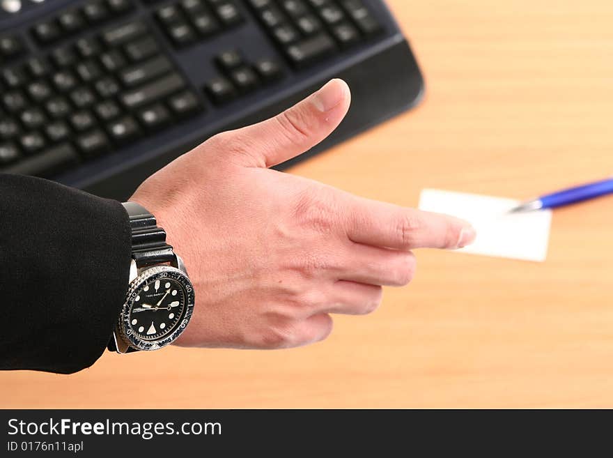 Business man reaching to shake hand with card and pen in background. Business man reaching to shake hand with card and pen in background