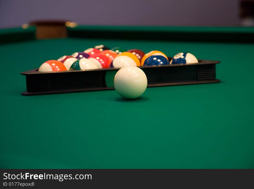 Color billiard balls on a green table in sport bar