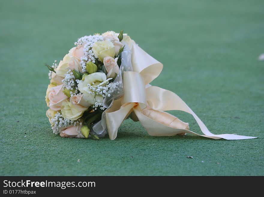 The beautiful wedding bouquet of roses lays on a grass.