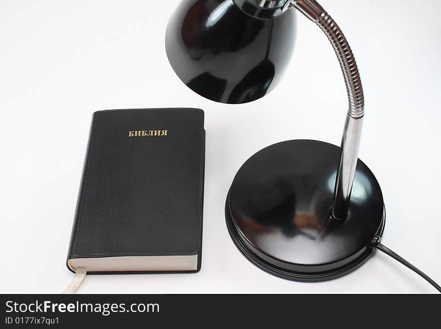 Black lamp stands next to the black book on white