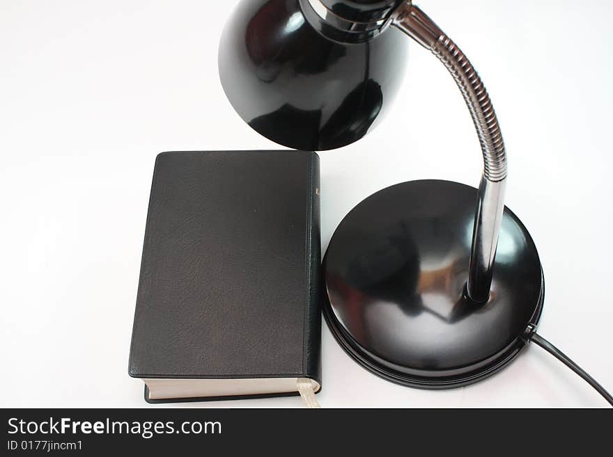 Black lamp stands next to the black book on white