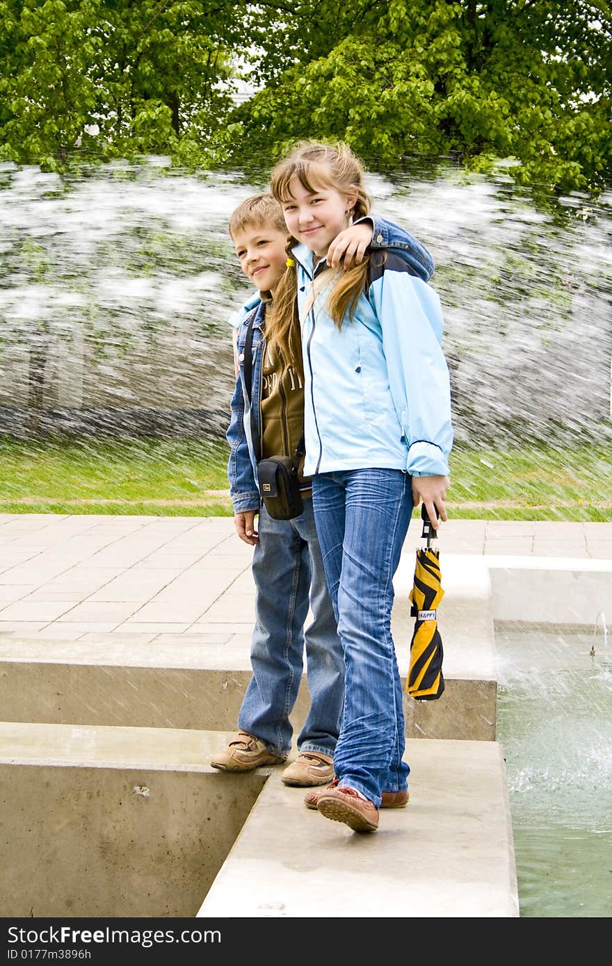 The boy and the girl stand against a fountain. The boy and the girl stand against a fountain