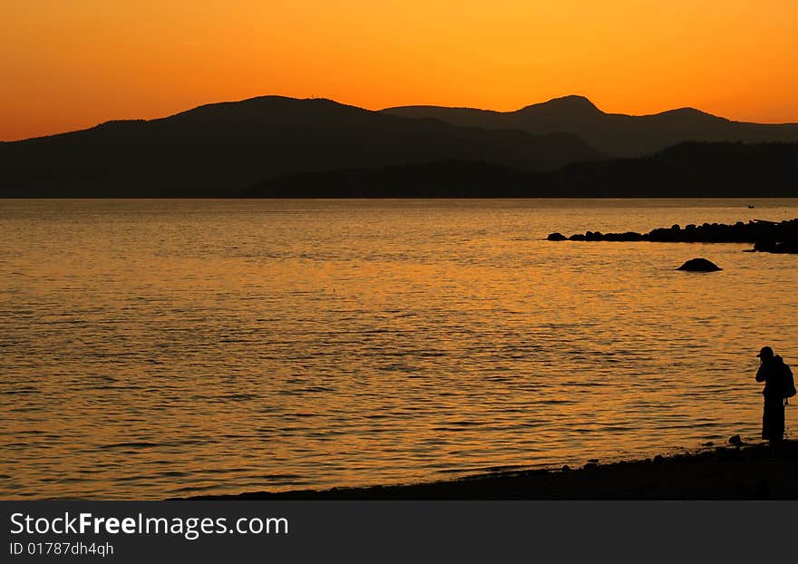 Silhouette of a man standing in a beach looking at a beautiful sunset