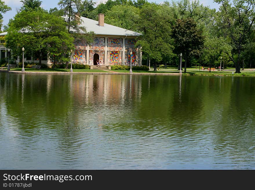 View of building in the park from across a pond which is reflecting the building.