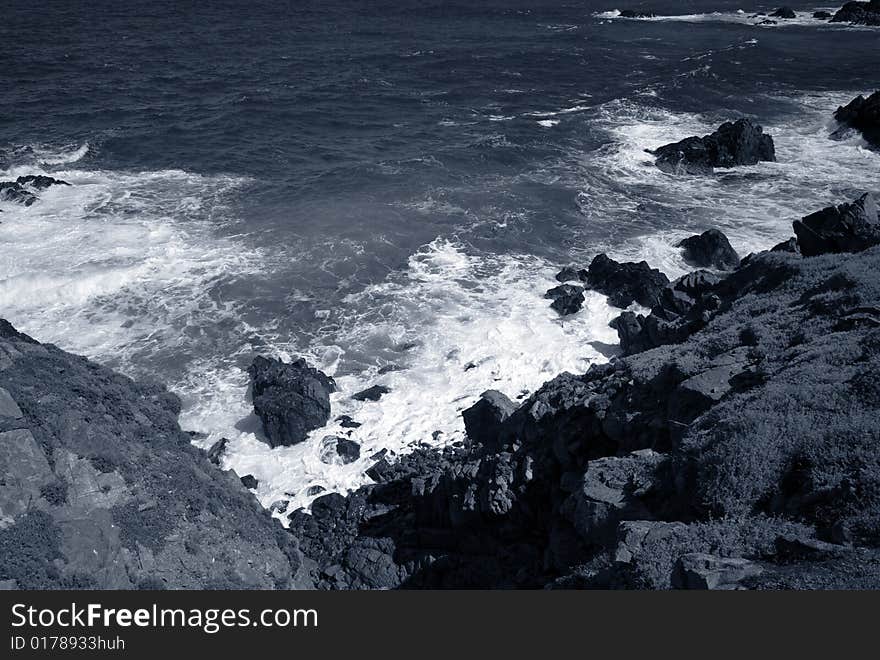 Blue Coastline. Where the waves crash against the rock cliff