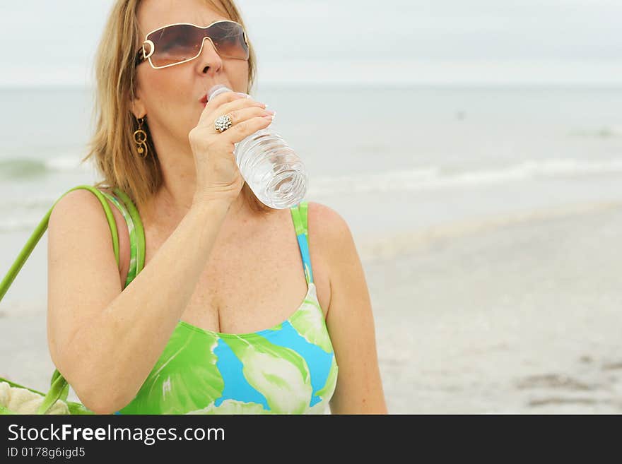 Shot of a woman drinking water at the beach