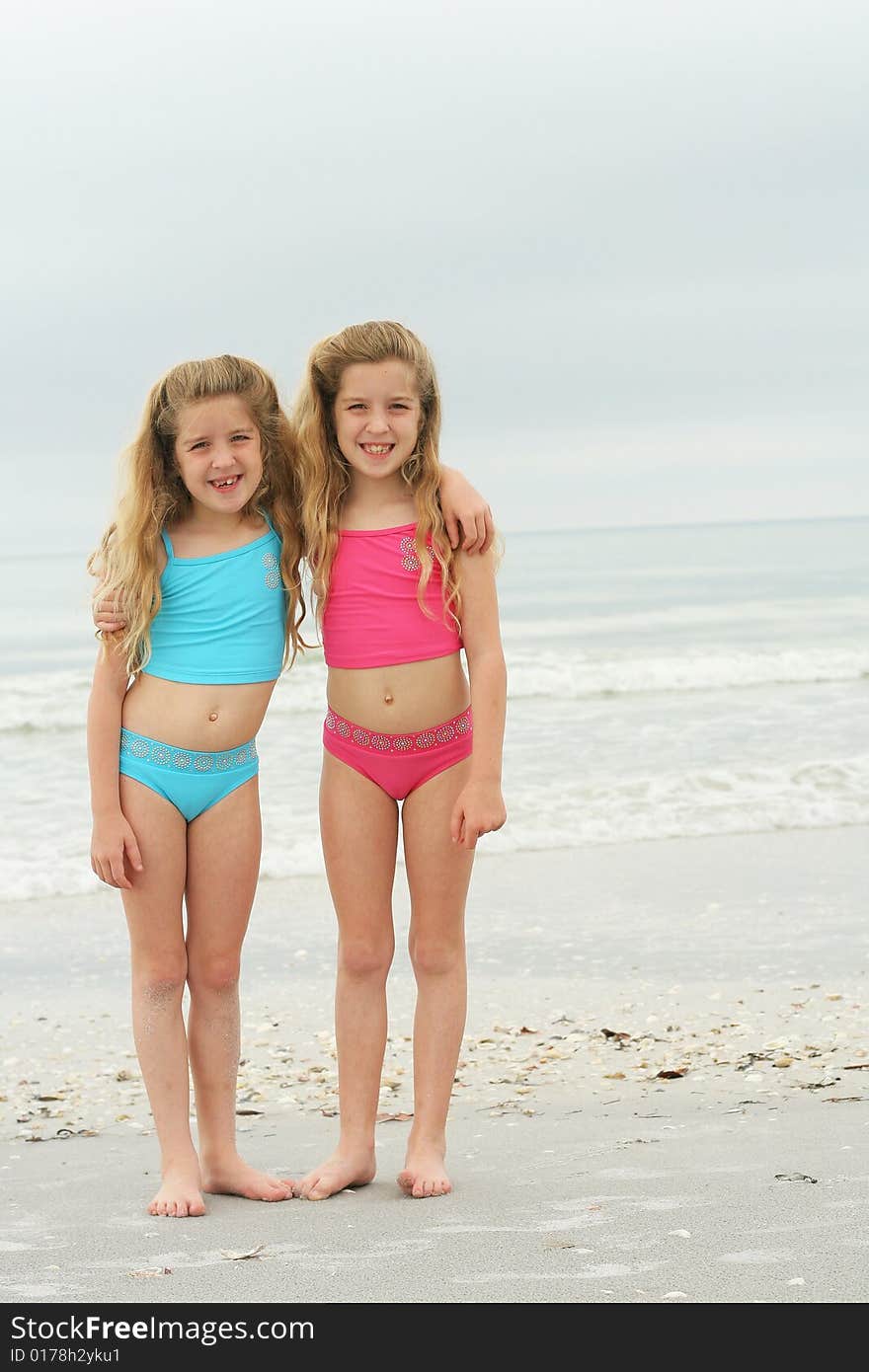 Shot of twin sisters at the beach vertical