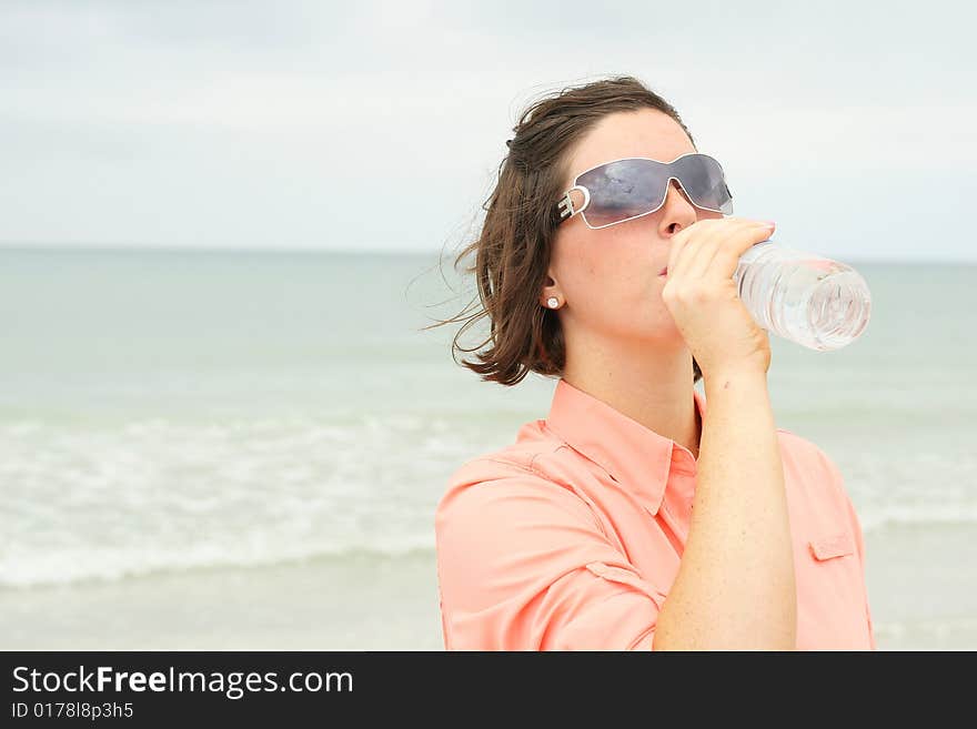 Beautiful brunette drinking water at the beach