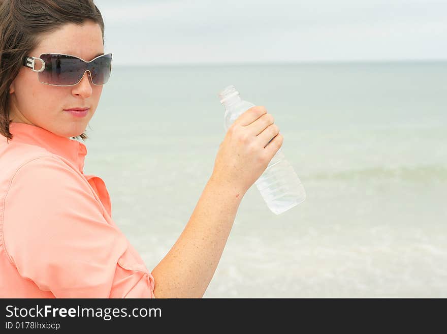 Shot of a girl drinking bottled water at the beach