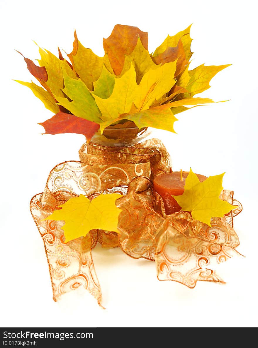 Bright maple leafs arranged in a glass vase with ribbon and candle. Bright maple leafs arranged in a glass vase with ribbon and candle