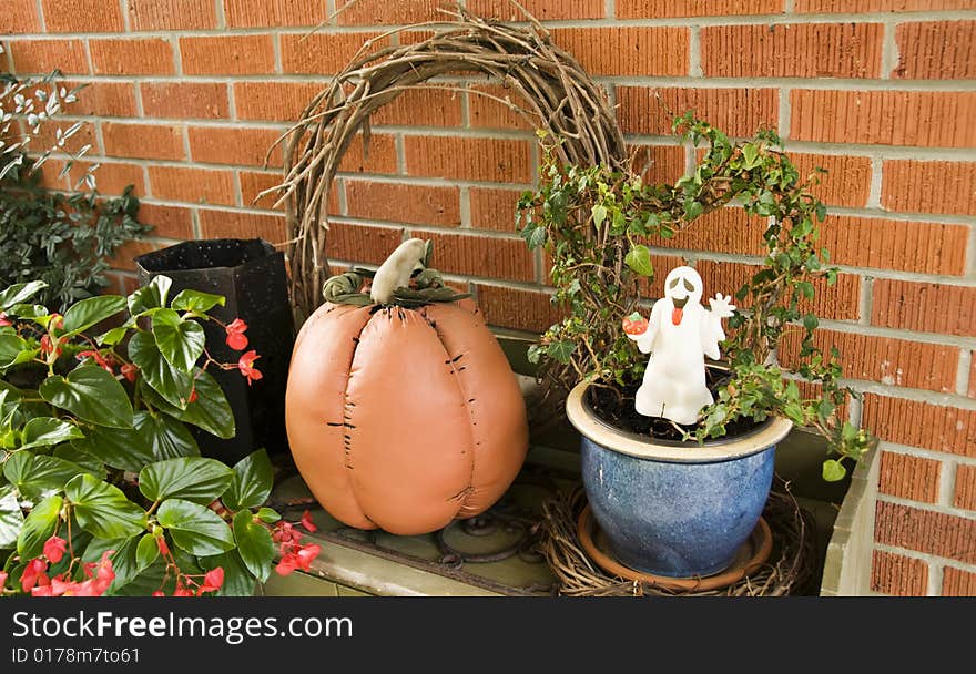 A ghost and pumpkin adorn potted plants. A ghost and pumpkin adorn potted plants.