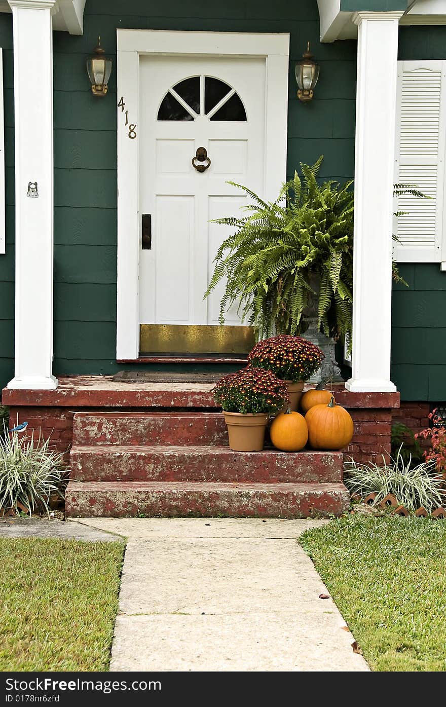 A welcoming entryway with a boston fern, mums and a pumpkin. A welcoming entryway with a boston fern, mums and a pumpkin.