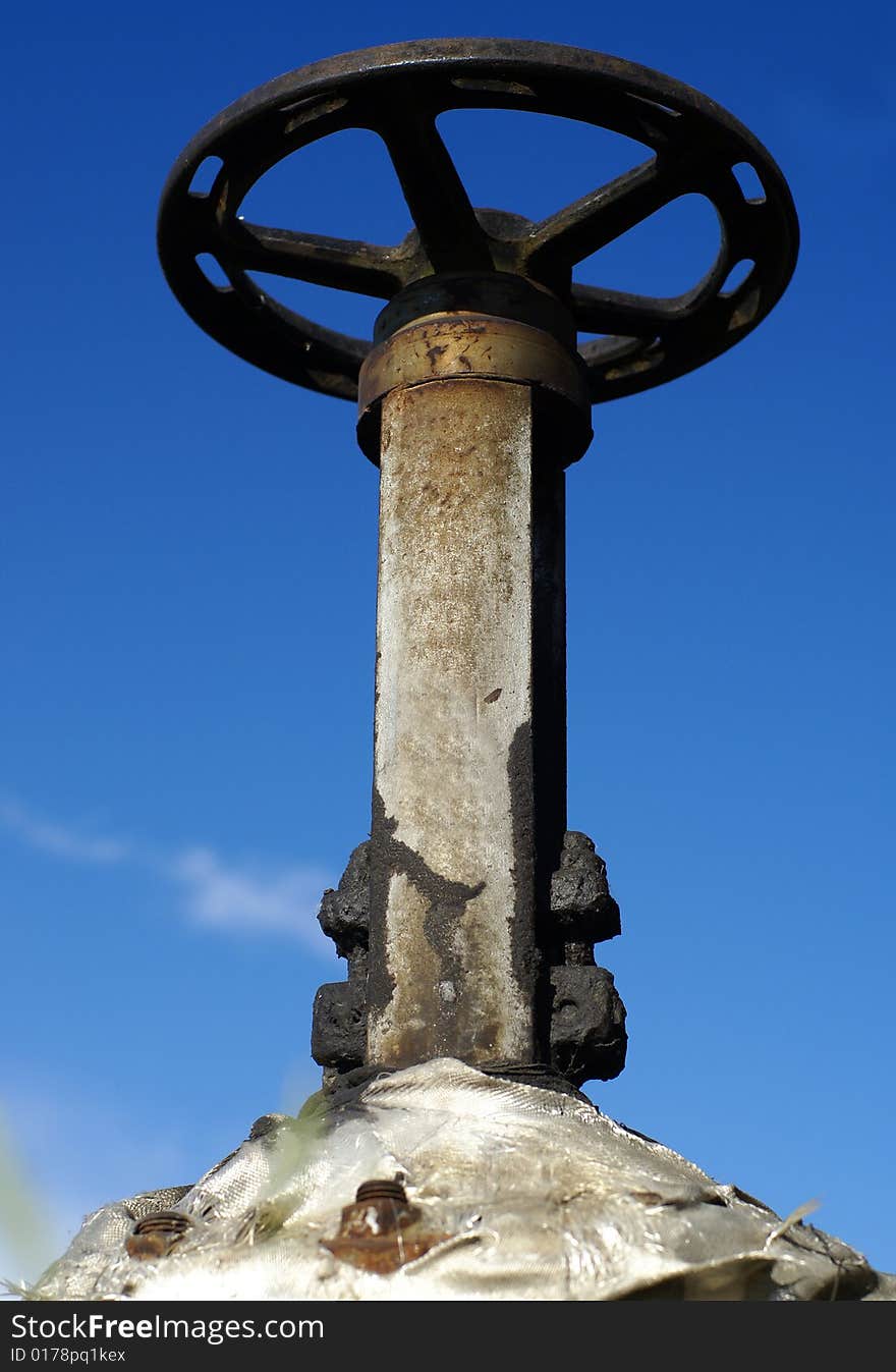 Industrial oil pipeline valve against blue sky. Industrial oil pipeline valve against blue sky