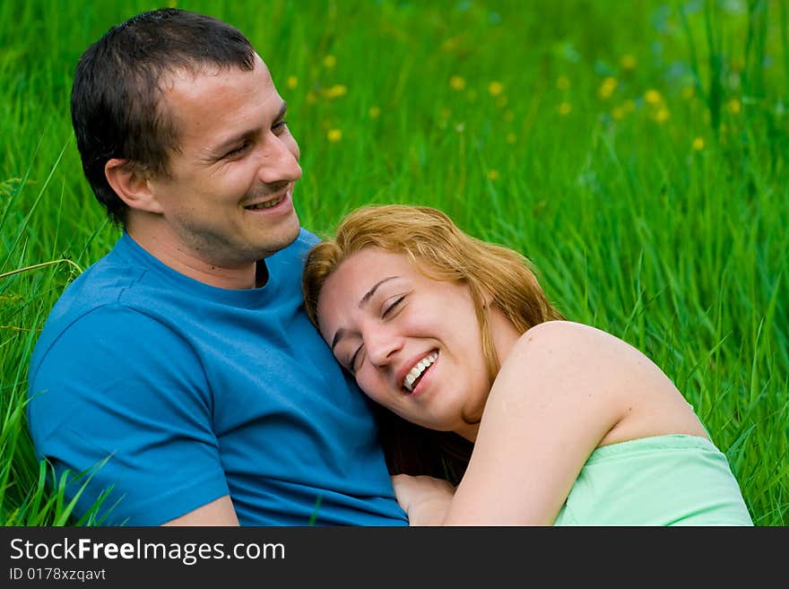 Portrait of a young loving couple laughing in grass. Portrait of a young loving couple laughing in grass