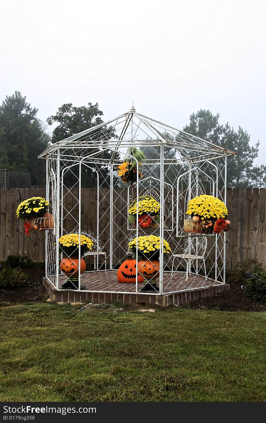 A White gazebo decorated for fall with mums, pumpkins and flowers. A White gazebo decorated for fall with mums, pumpkins and flowers