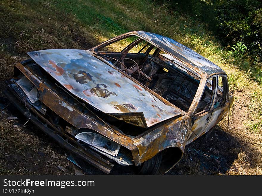 An abandoned car burned out and left in a field. An abandoned car burned out and left in a field