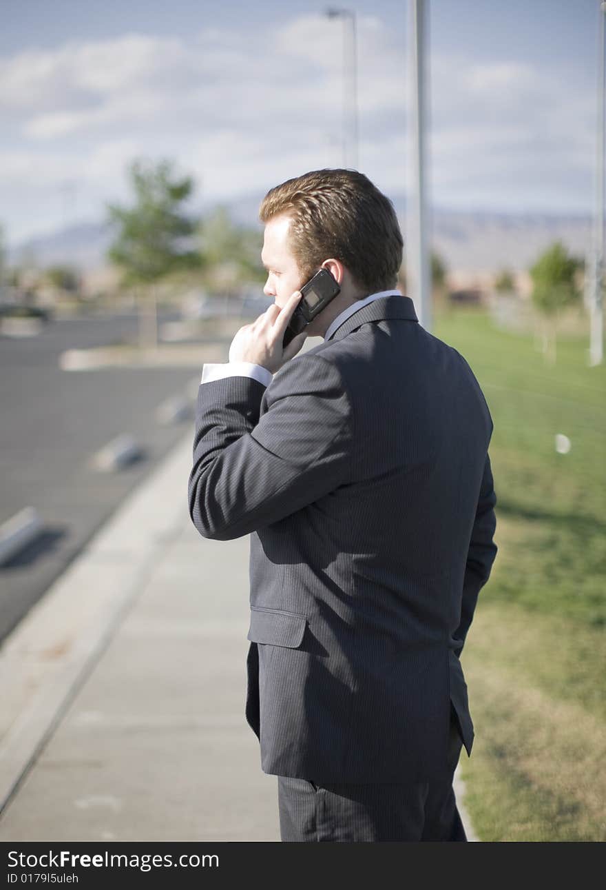 Businessman talking on his cell phone about business while standing outside in his business suit. Businessman talking on his cell phone about business while standing outside in his business suit