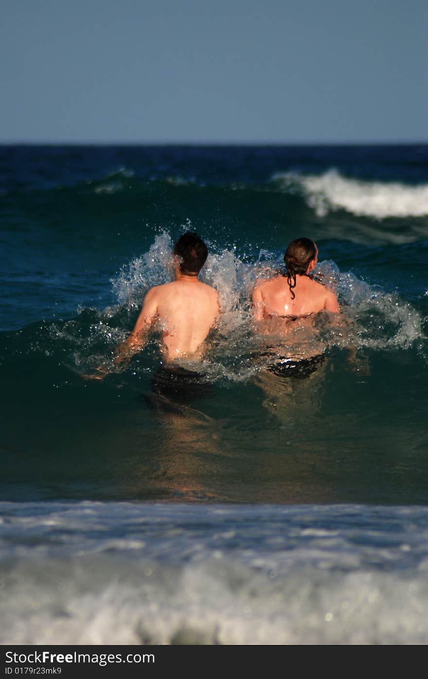 A young couple in the surf with copy space above and below. A young couple in the surf with copy space above and below