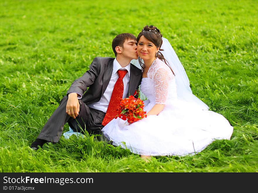 Groom and bride sitting on the green grass. Groom and bride sitting on the green grass.