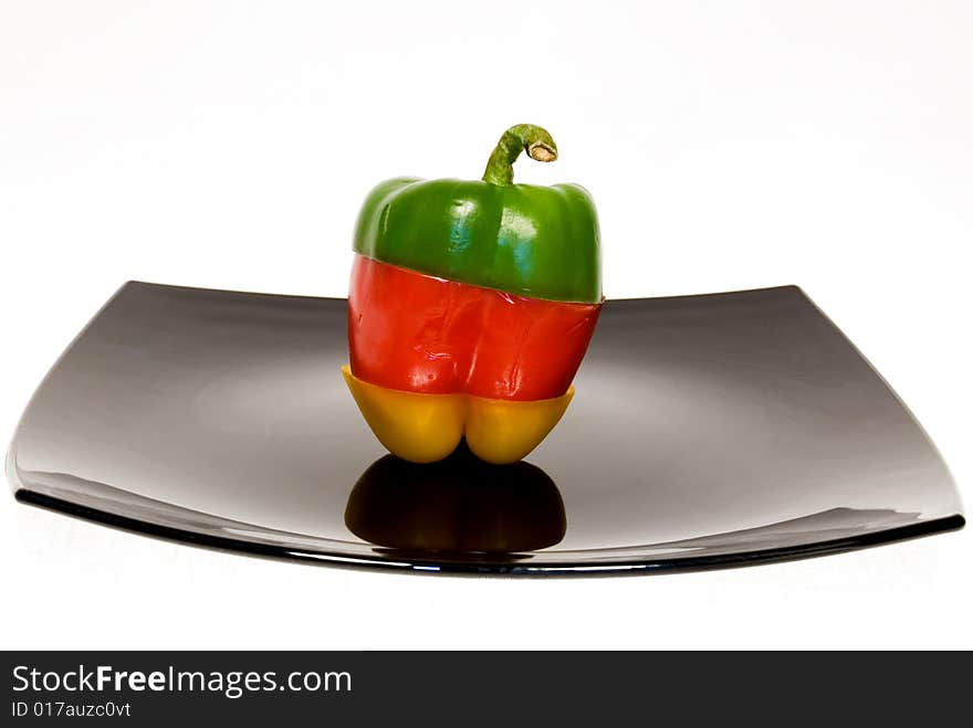 Tricolor paprika on black plate separated on white background