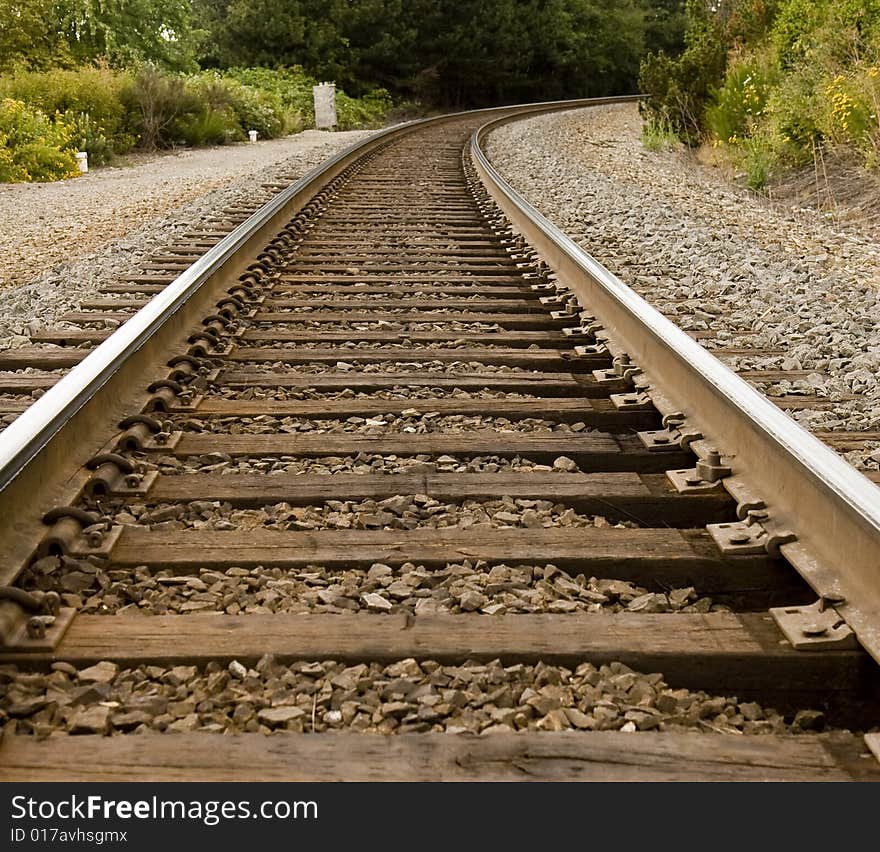 Train tracks disappearing around a curve in the trees. Train tracks disappearing around a curve in the trees