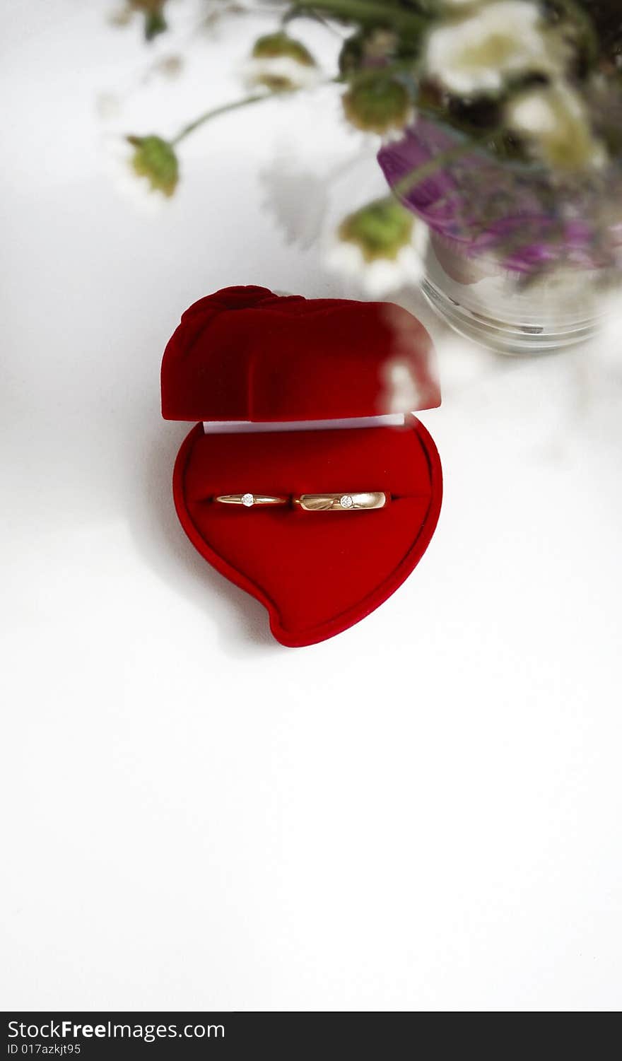 Gold wedding rings with brilliants in the red velvet case on the white background