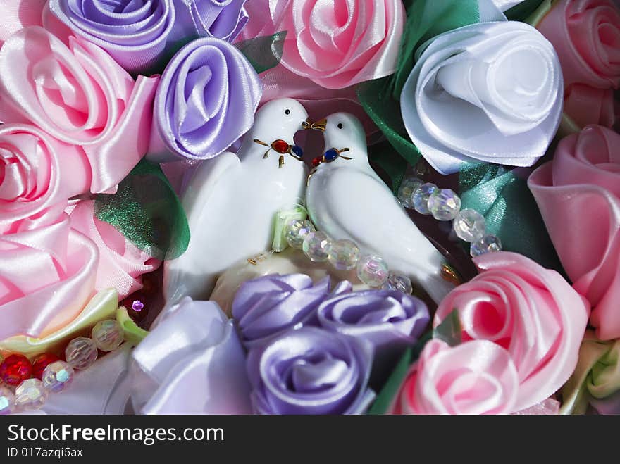 Porcelain figurine of  dove couple surrounding with silk flowers. Porcelain figurine of  dove couple surrounding with silk flowers.