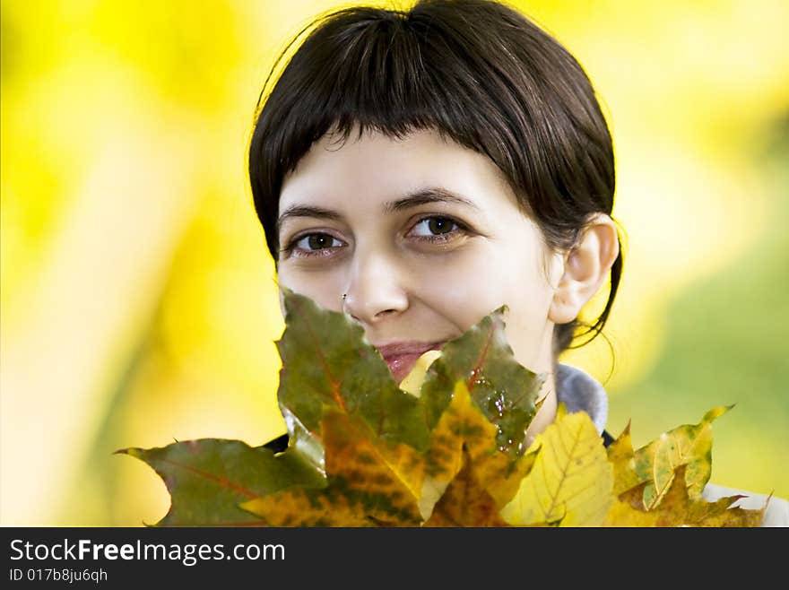 Young woman with maple leaves in hand