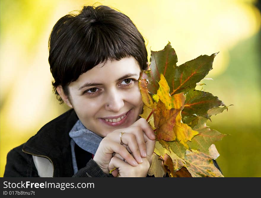 Young woman with maple leaves in hand