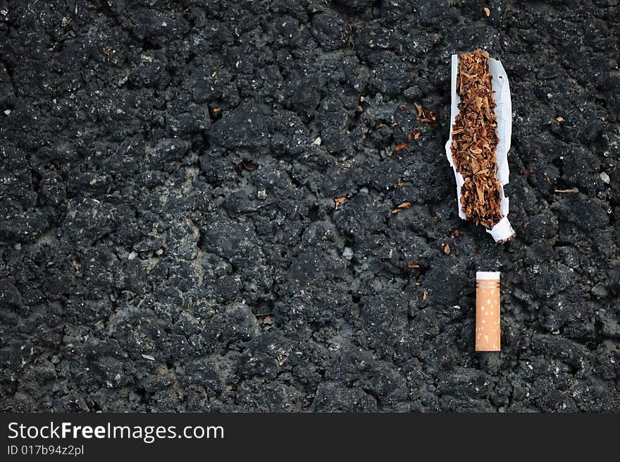 Torn apart cigarette on bitumen surface. Torn apart cigarette on bitumen surface