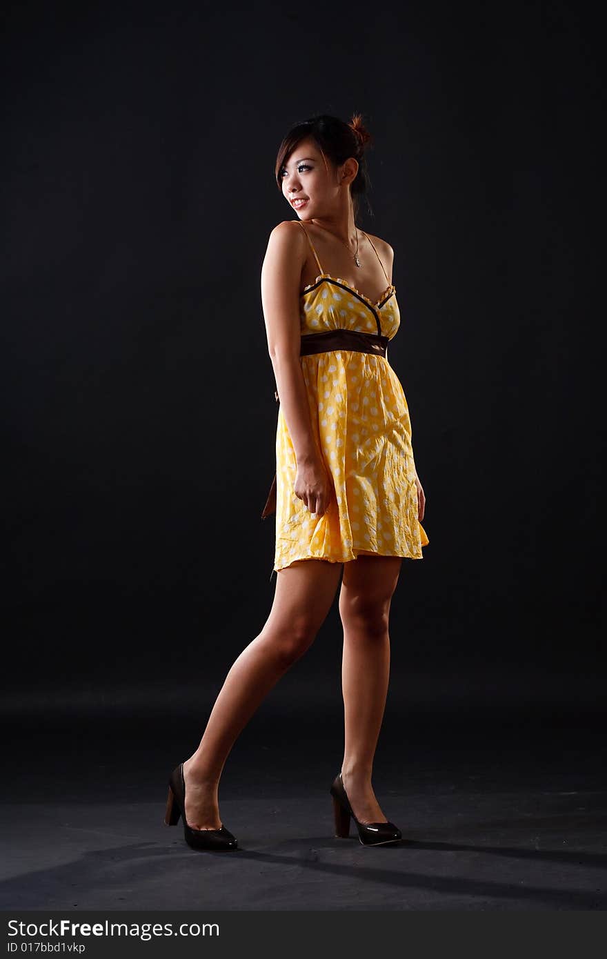 Asian girl in yellow polka dot dress look side way. Asian girl in yellow polka dot dress look side way