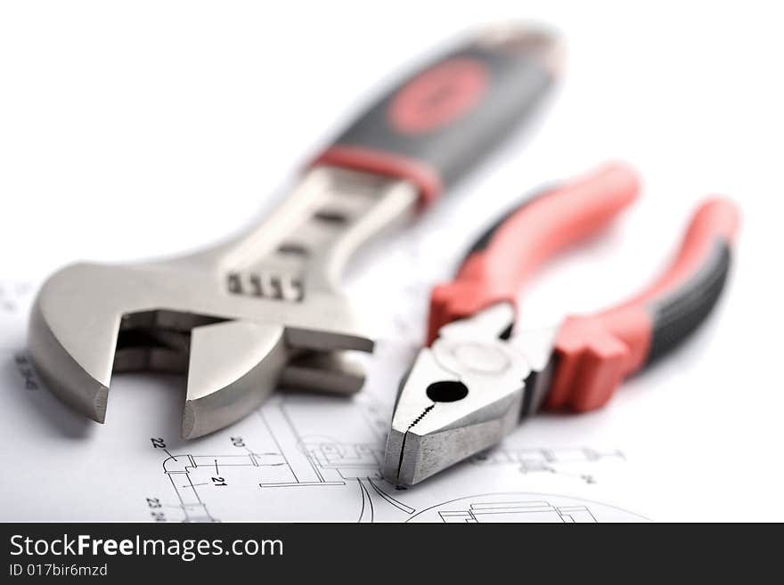 Wrench and pliers over technical drawing isolated on white