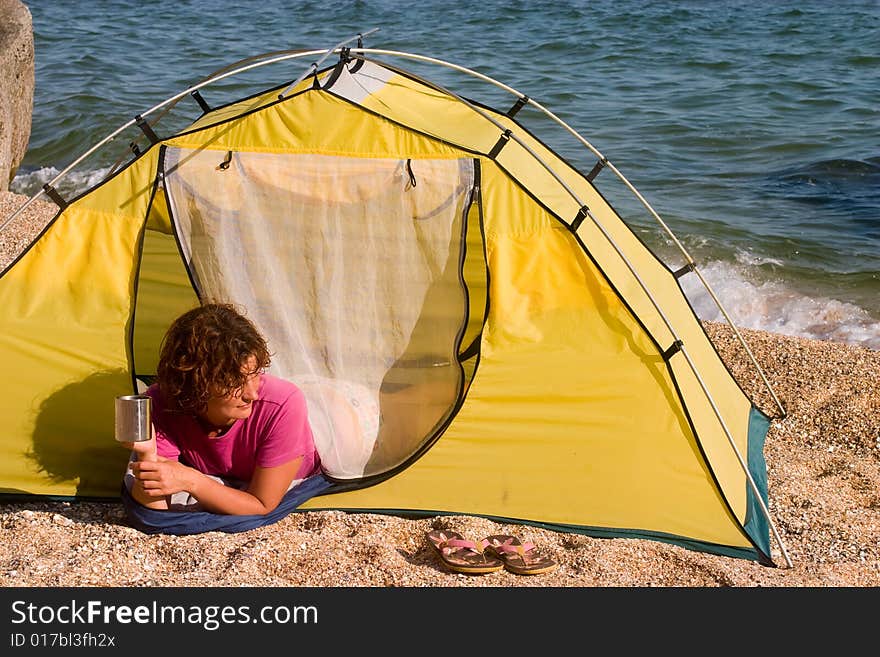 Girl with mug lying in the tent at sand sea shore. Girl with mug lying in the tent at sand sea shore