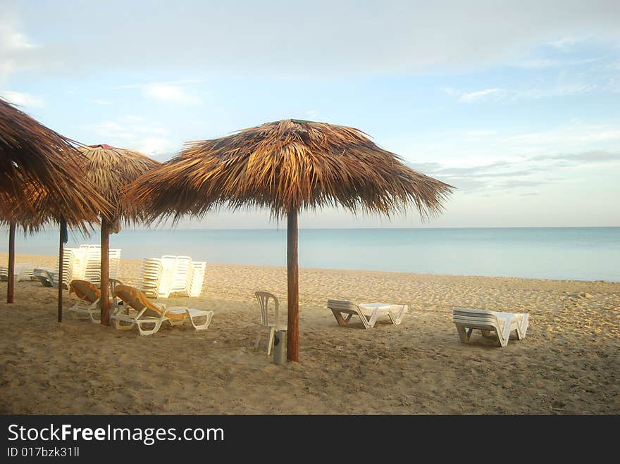 Empty tropical beach chairs on sand at shoreline. Empty tropical beach chairs on sand at shoreline