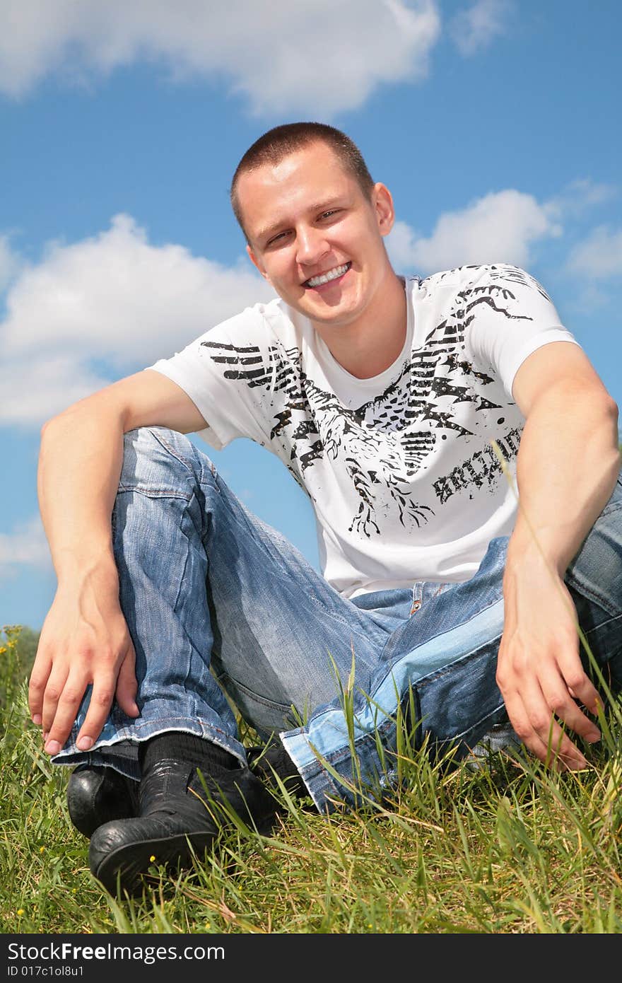 Young man sits on grass