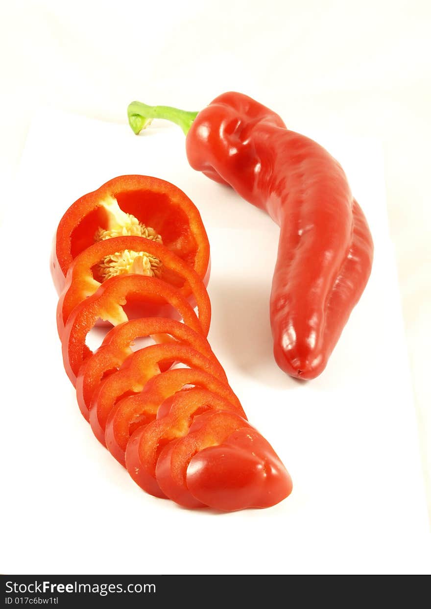 A food composition of chili and a red sliced pepper on isolated white background. A food composition of chili and a red sliced pepper on isolated white background