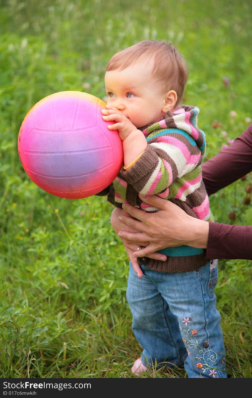 Mother hold baby with ball on grass