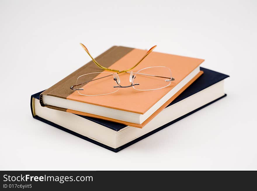 Two closed books and a pair of glasses