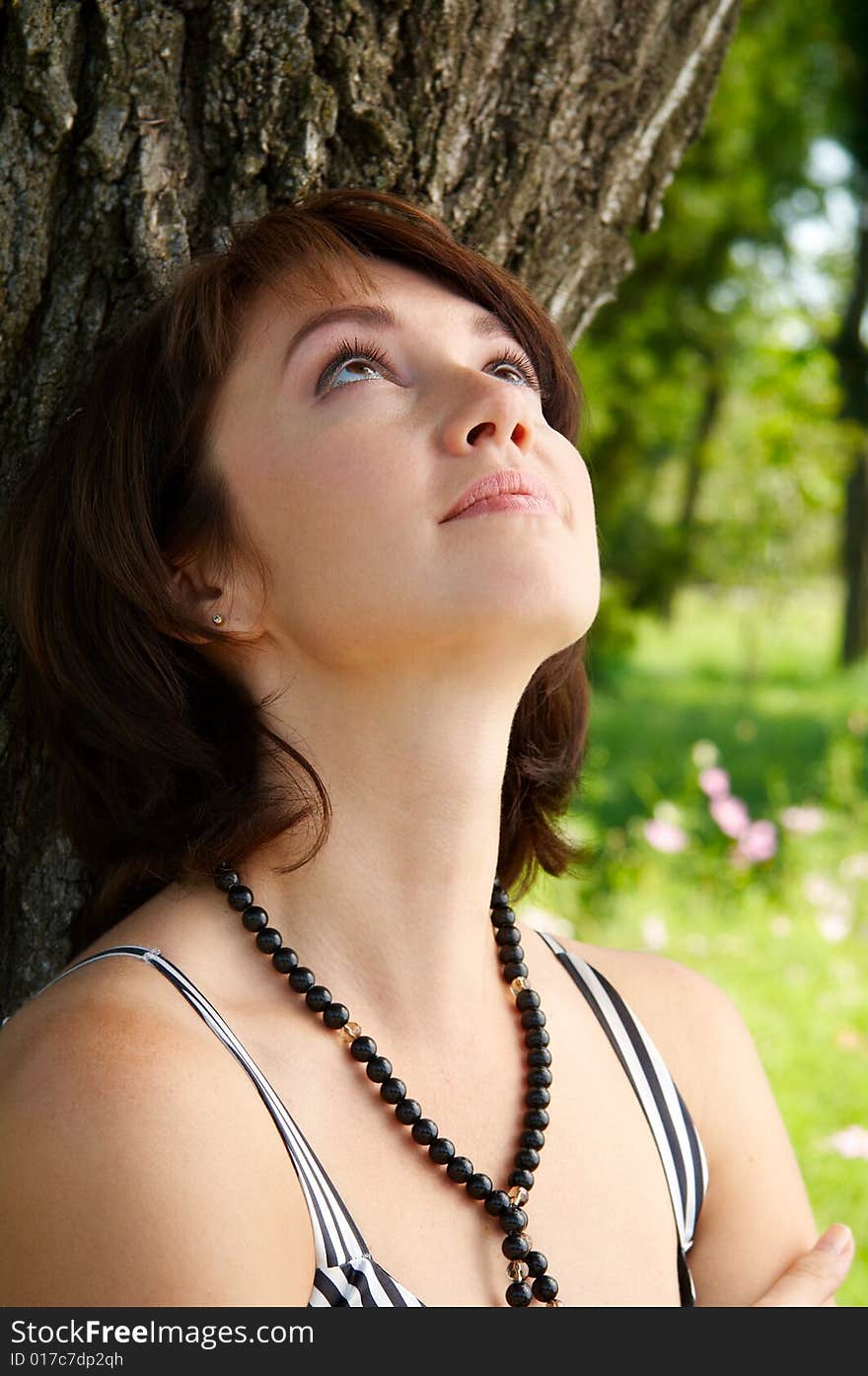 Young beautiful woman costs near a tree