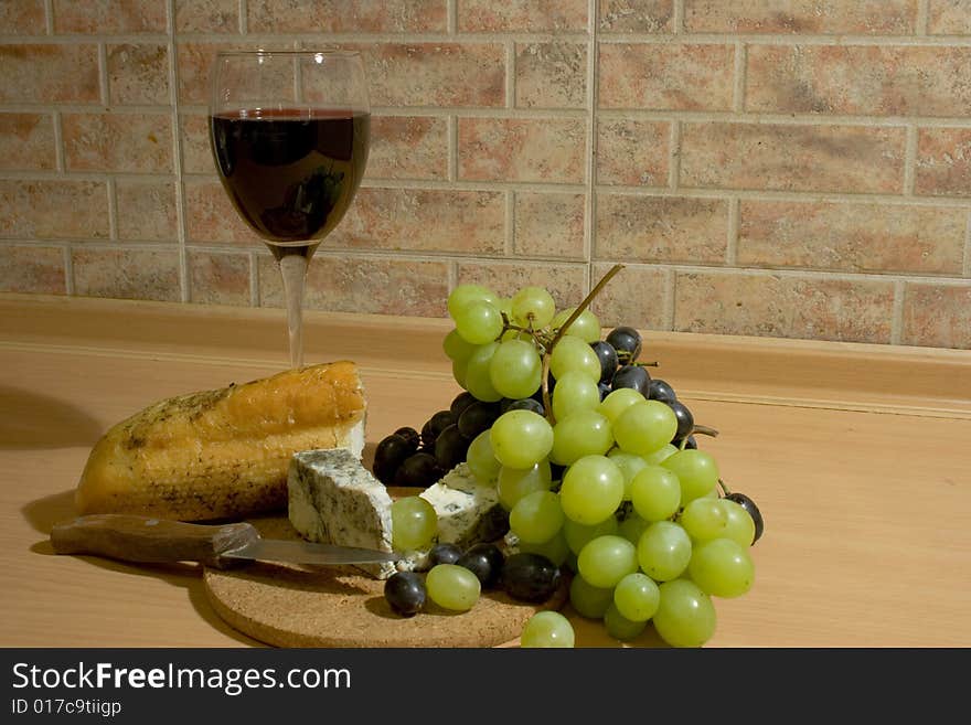 A glass of red wine with cheese, bread and grapes. A glass of red wine with cheese, bread and grapes