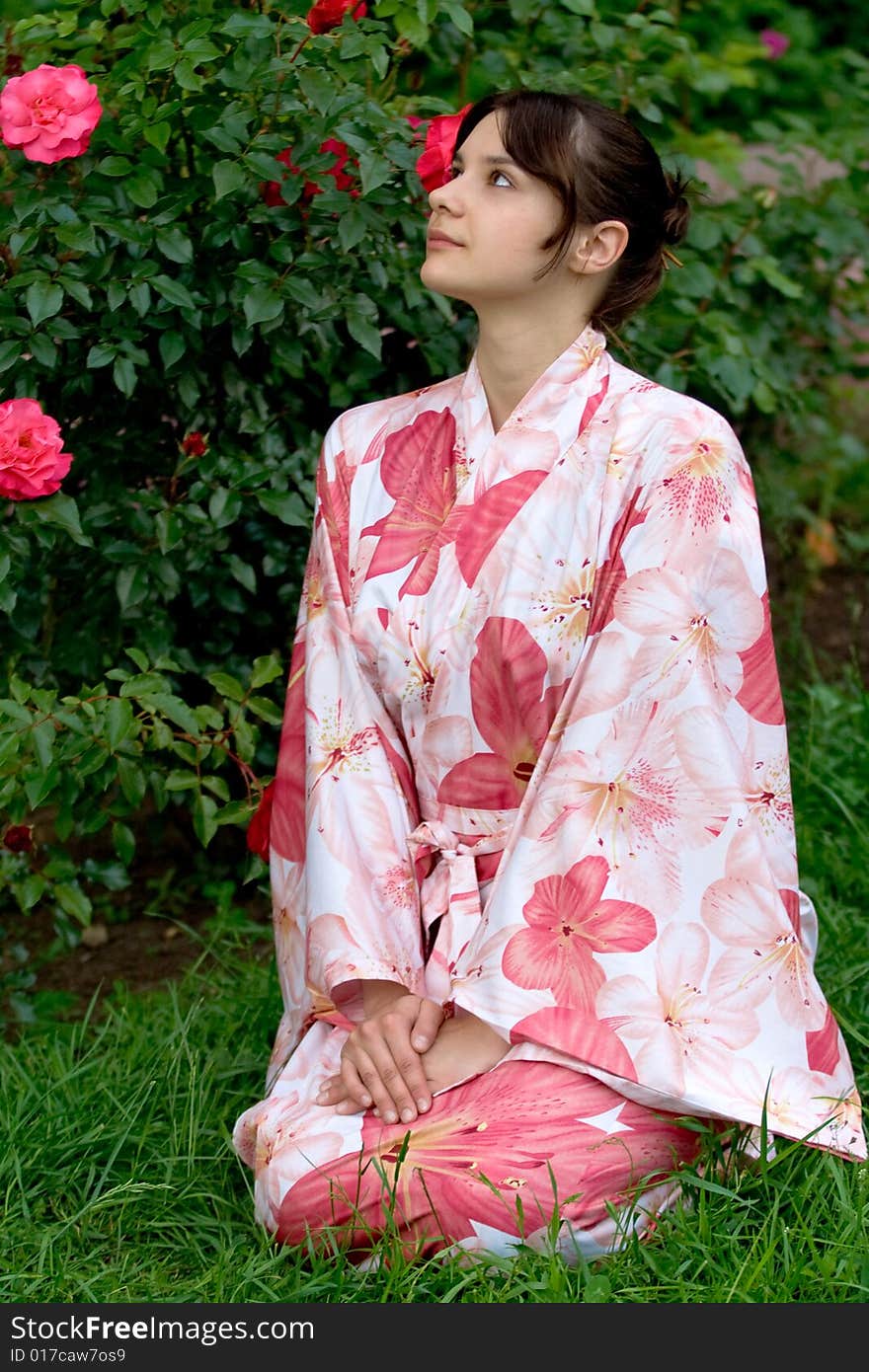 Girl in a pink yukata near rosebush. Girl in a pink yukata near rosebush