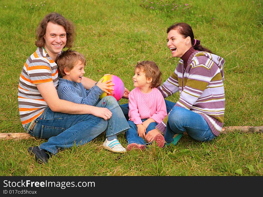 Family of four sits on grass