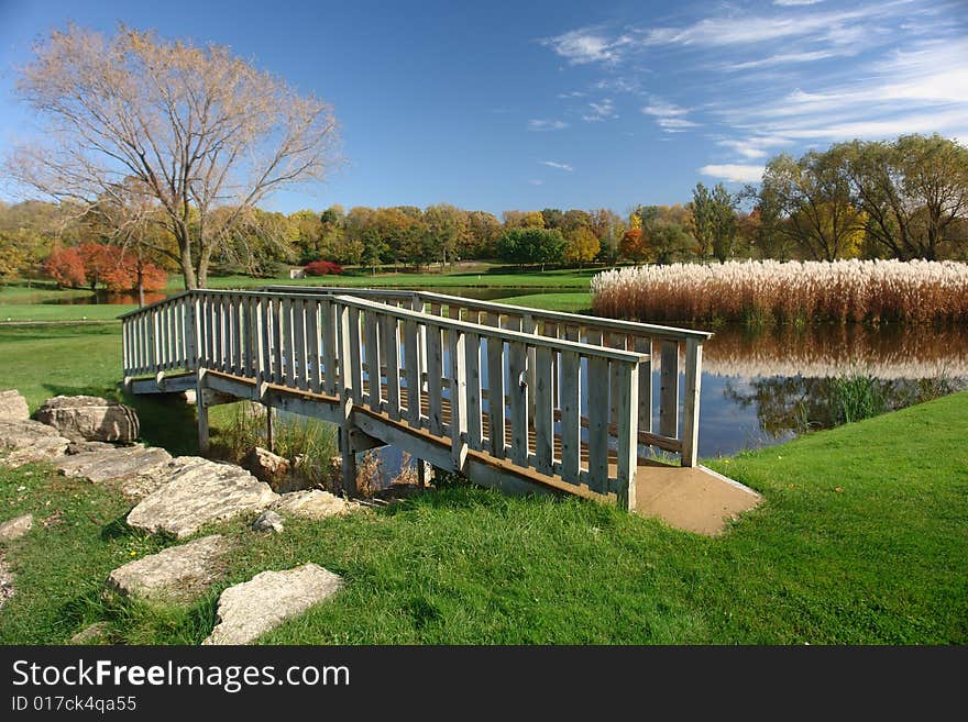 A picture of a small footbridge over pond in rural country