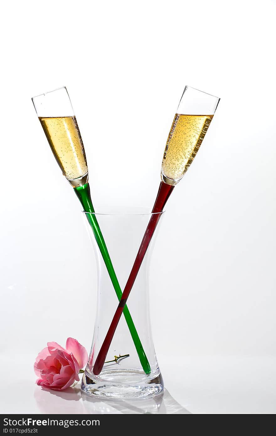 Two flutes of champagne and rose on white background