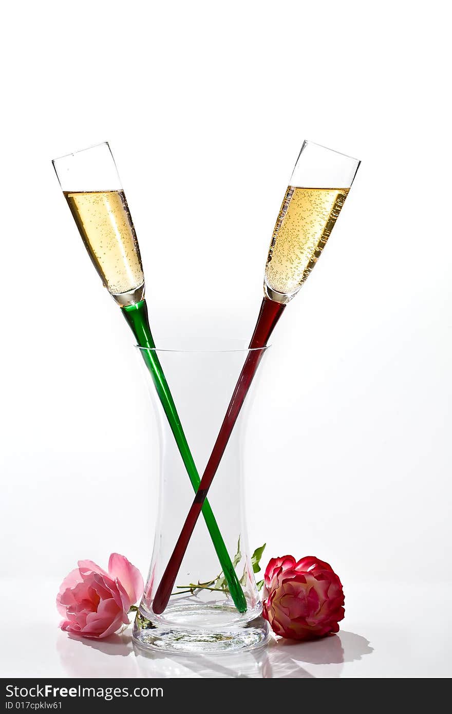 Two flutes of champagne and rose on white background