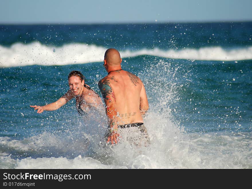 A young couple play in the surf. A young couple play in the surf