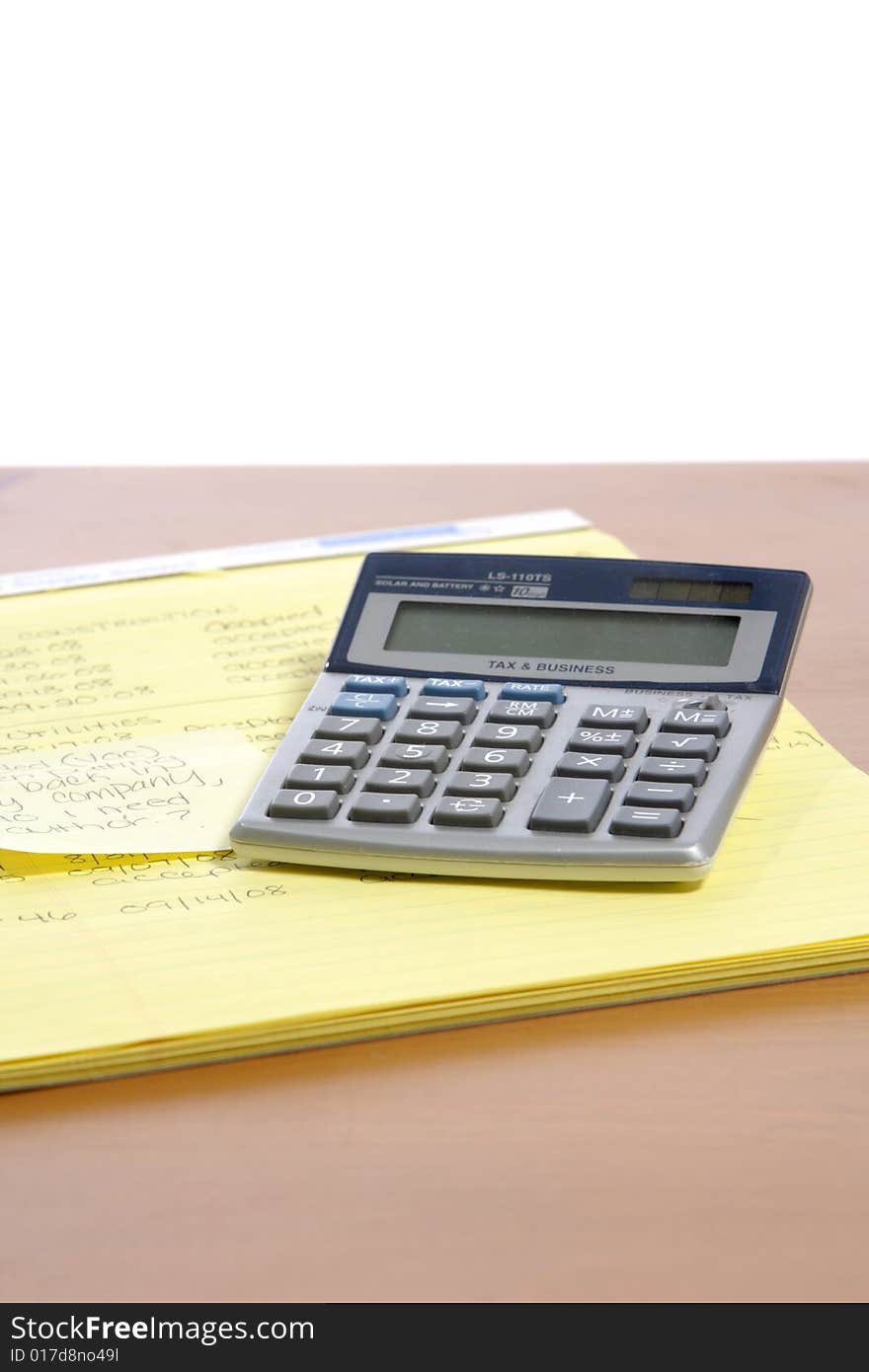 A calculator on a legal pad in an office. A calculator on a legal pad in an office