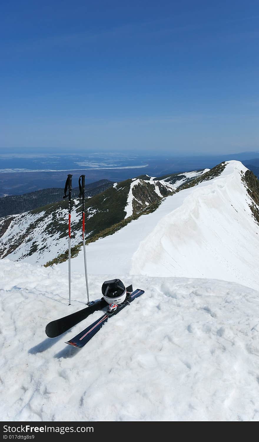 A pair of skis and helmet on the top of snowy mountain