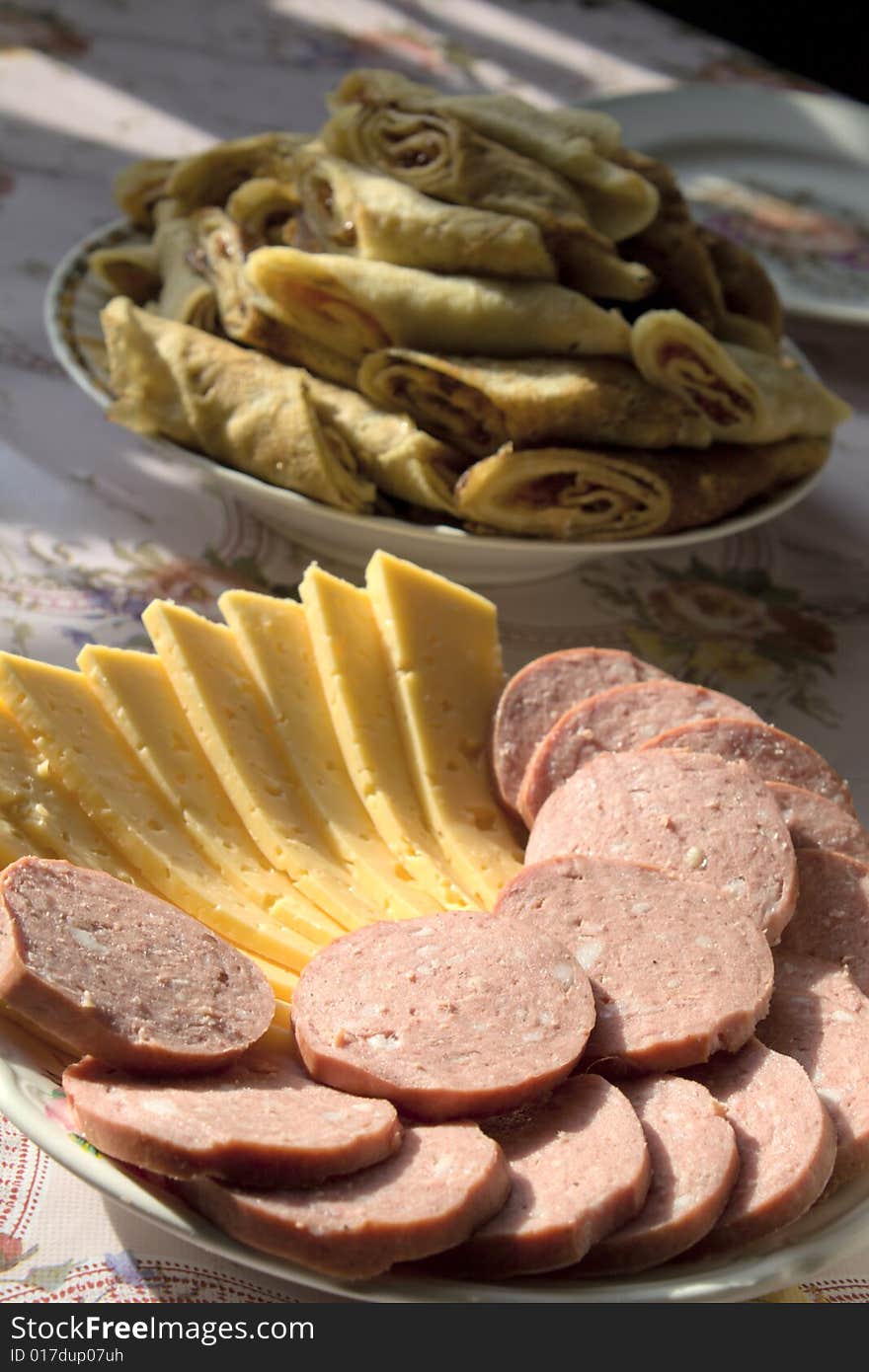 Sausage and cheese are cut on a plate. Sausage and cheese are cut on a plate